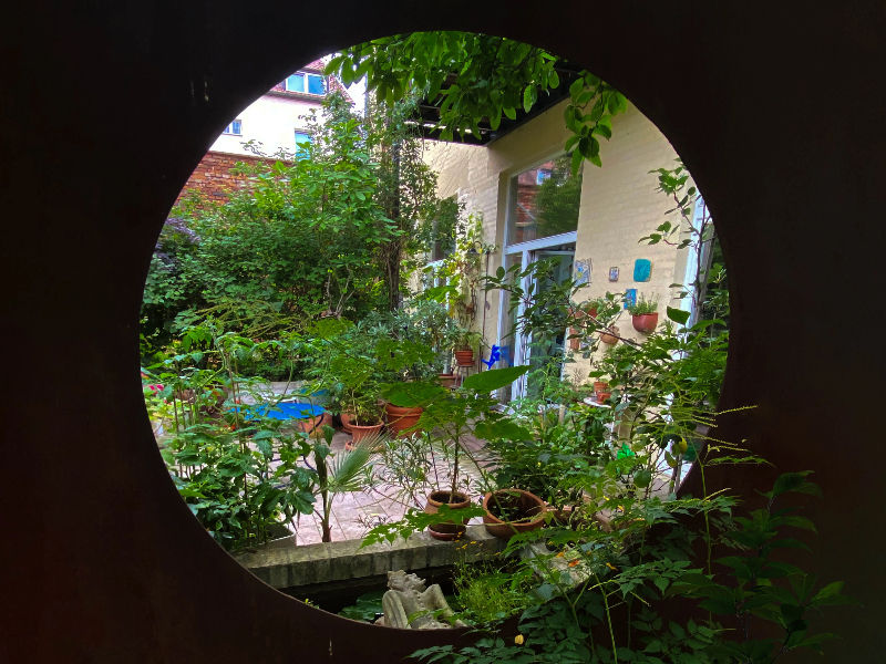 Gartenhaus und Rosenbogen mit pinken Rosen
