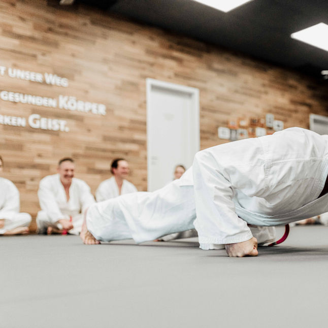 Kampfsportschüler führt Liegestütze als Kraftübung im Training aus