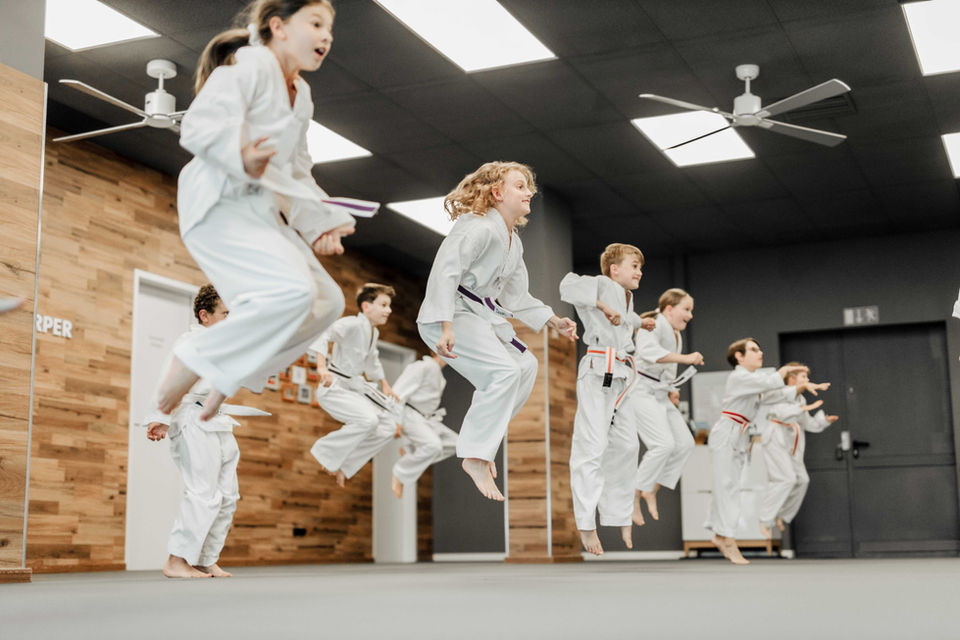 Gruppe von Kindern springt gleichzeitig – Koordinations- und Krafttraining in der Taekwondoschule.