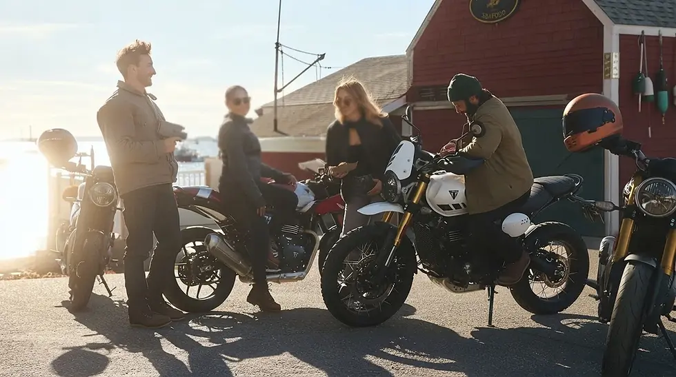 Outdoor photography, a group of friends interacting around motorcycles by a harbor. The scene is bright and casual with a spirit of adventure.