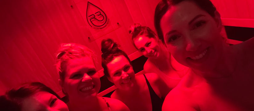 A group of women enjoying a private wellness experience in a red-lit room at R3 Recovery in San Diego