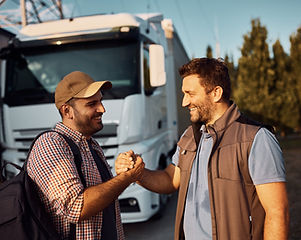 Happy truck driver and his coworker greeting while standing on parking lot. .jpg