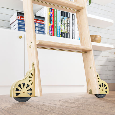 A close up of the stunningly detailed weight braked wheels from the Quiet Glide range of rolling library ladder hardware kits. The wheels in this image are finished in a summery polished brass with contemporary wedge cut outs showing the black rubber wheels in a circular pattern.