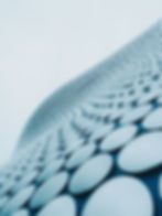 Abstract architectural photography showing a blue curved facade covered with round aluminum discs