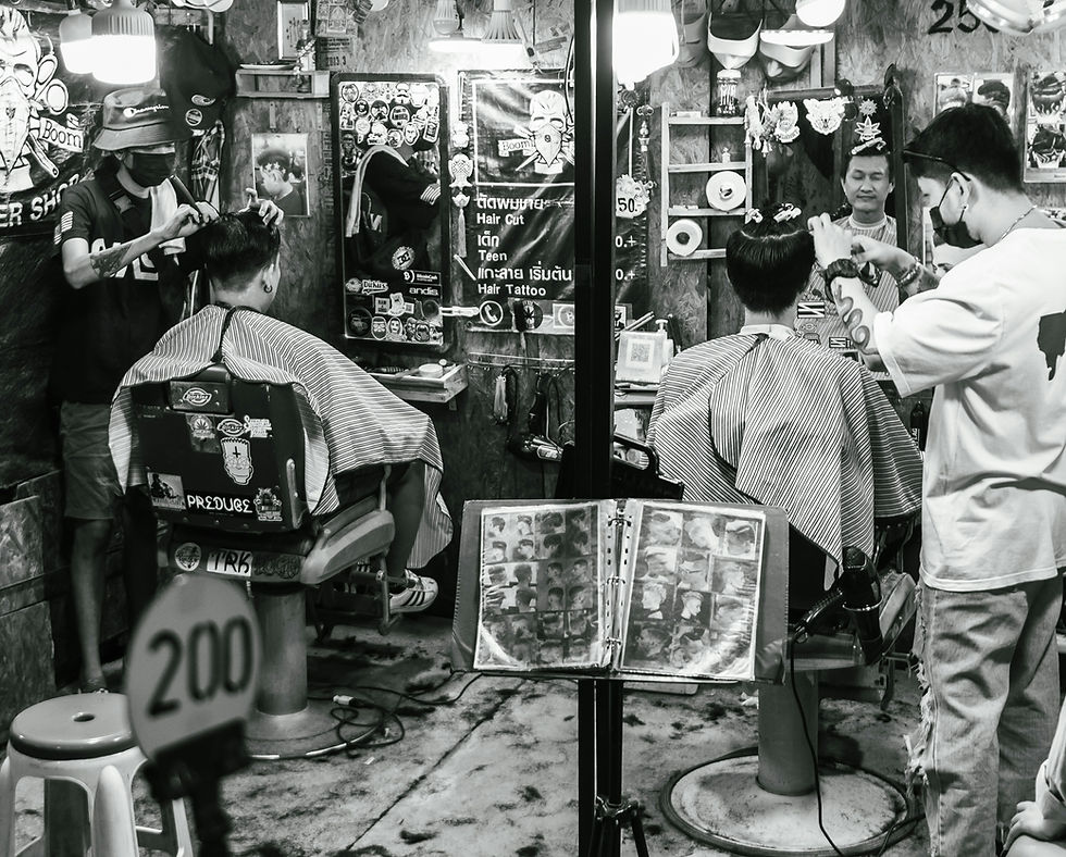 Two men get haircuts in a barbershop with vintage decor. Barbers wear masks. A poster with haircut options hangs on the wall.