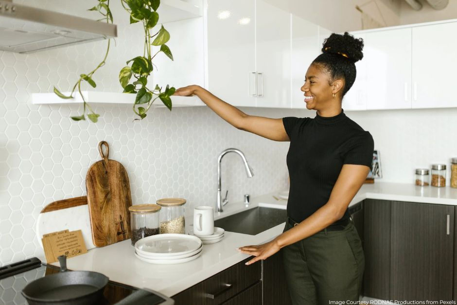 Happy woman cleaning kitchen shelf