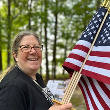 Woman holding U.S. Flags at Suwanee Town Cemetery.