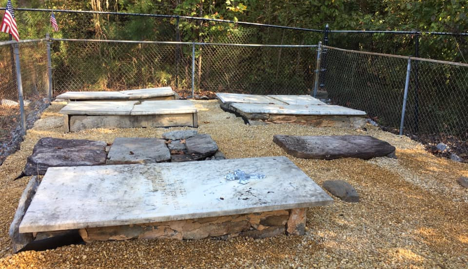 Historic flat grave markers enclosed by a chain-lin fence at Kile-Benson Cemetery in Sugar Hill, Georgia.
