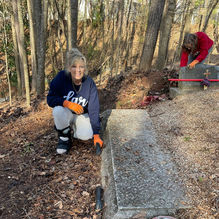 Volunteer cleaning a stone grave at Jackson Street Cemetery