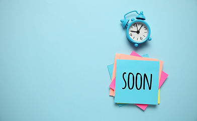 Blue alarm clock and paper reminder,coming soon. Time management, priorities, efficiency,