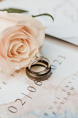 Elegant wedding rings atop a wedding invitation marked with a wedding date, alongside a delicate pale pink rose in North Yorkshire