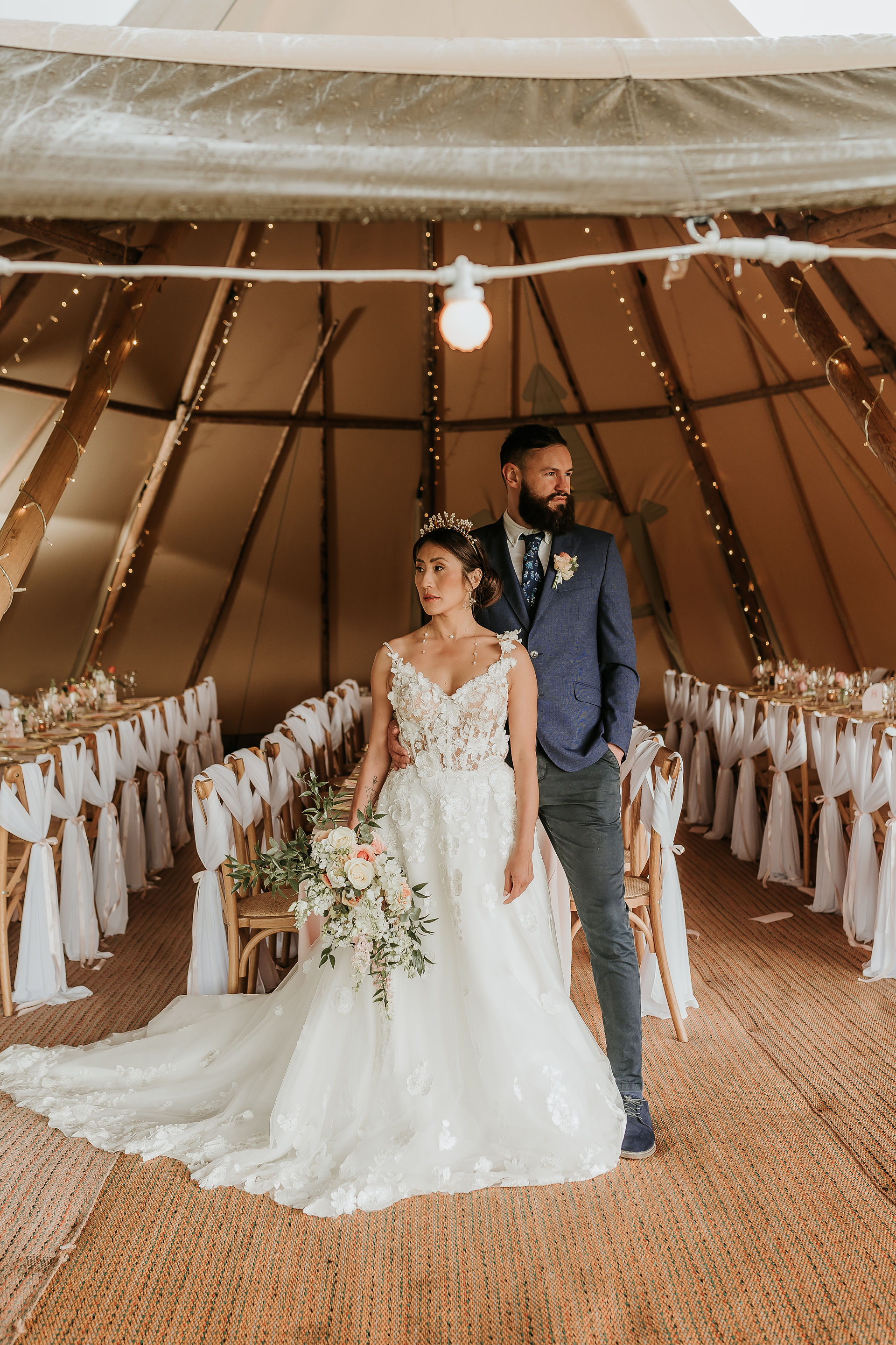 Tipi wedding bride holding bouquet standing next to groom