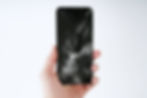 A man holds a smartphone in his hand with a broken screen on a white background.jpg
