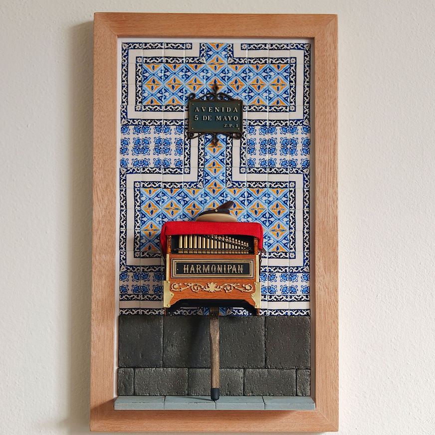 Diorama en marco de un organillero miniatura montado sobre la fachada de la Casa de los Azulejos de la CDMX