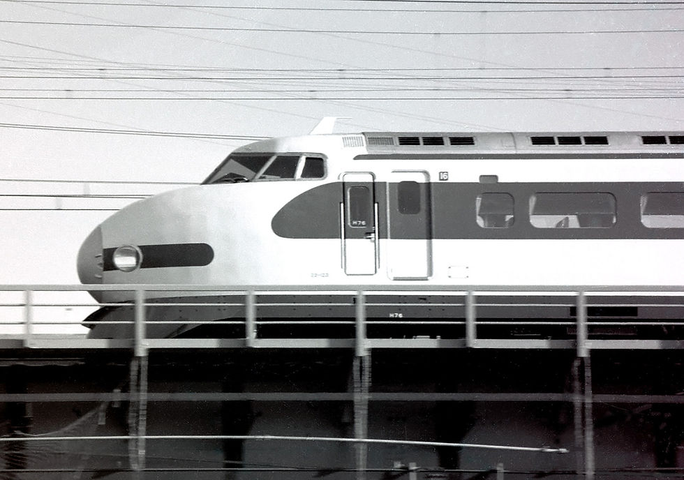 Bullet train on elevated track, black and white. Wires above, train moving left, windows and door number "16" visible.