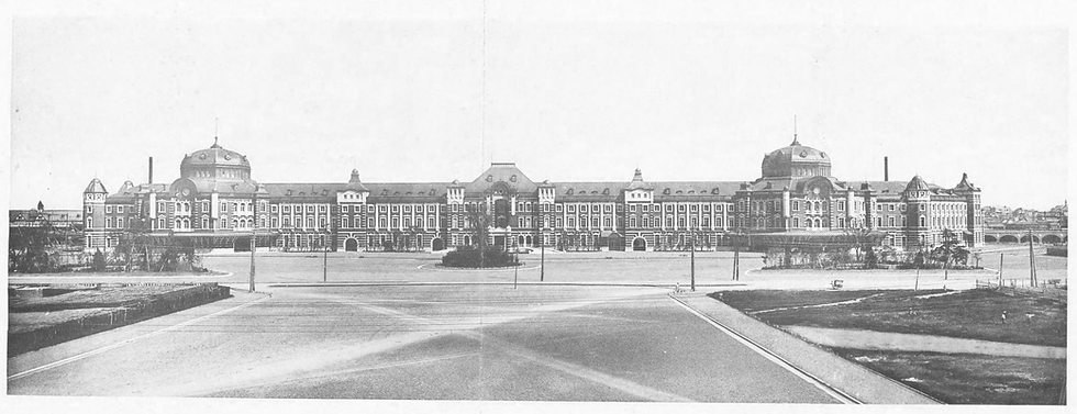 Historic, symmetrical station building with domes and arches in a vast, open plaza. Black and white, capturing a calm, grand atmosphere.