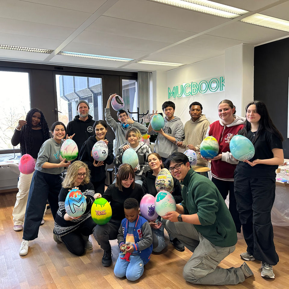Gruppenfoto eines Workshops mit Erwachsenen und Kindern, alle halten bemalte Ballons.