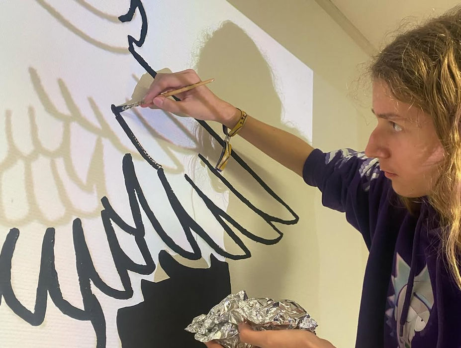 Nahaufnahme einer Pfadfinder, der konzentriert eine Wand bemalt – Detailarbeit am Kunstwerk.