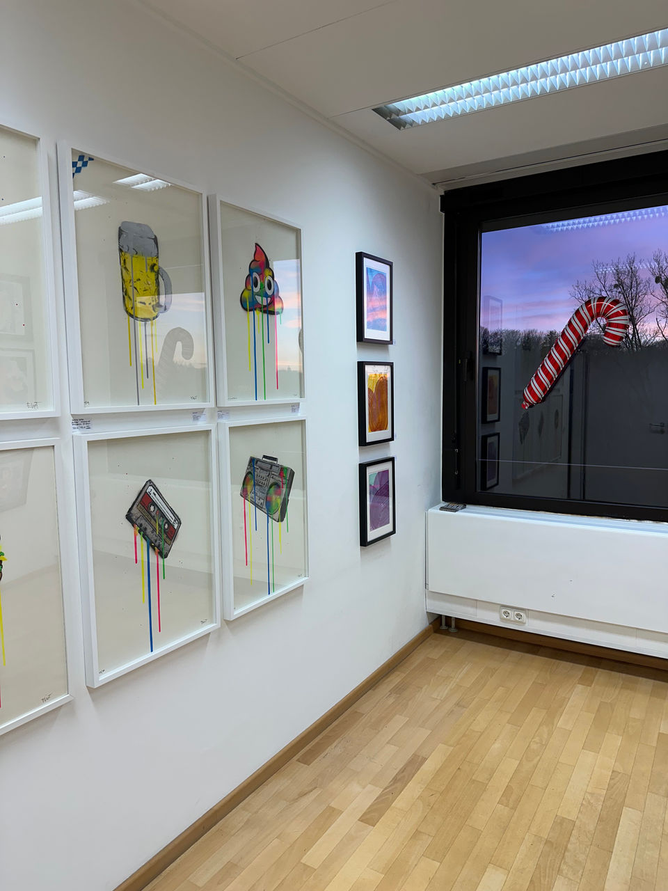 Galerieraum mit großformatigen Zeichnungen, draußen Blick auf ein beleuchtetes Gebäude.