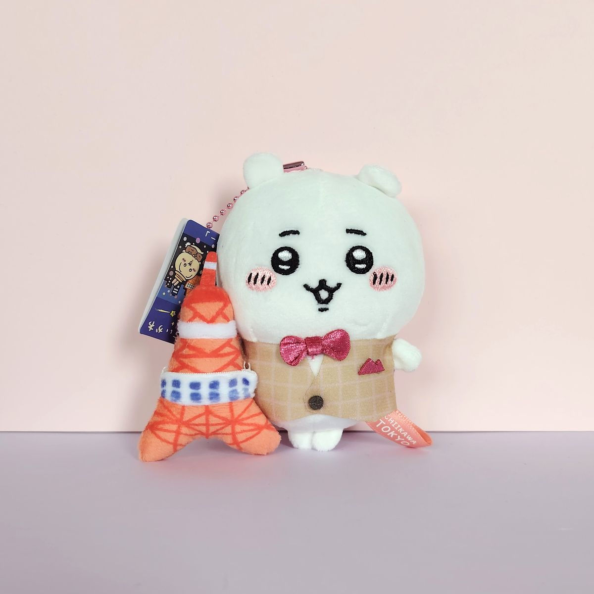 Peluche Chiikawa en costume rose avec nœud papillon et mini Tokyo Tower