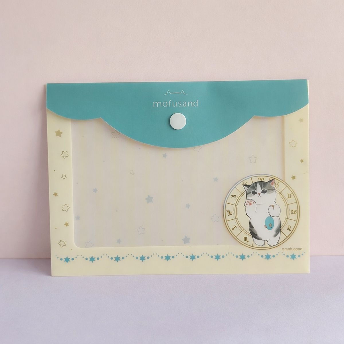 Face avant de la pochette Mofusand crème et turquoise avec chat dans une roue du zodiaque