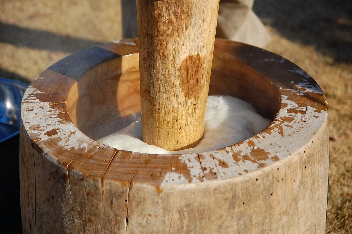 Mochitsuki traditionnel japonais, préparation du mochi en pilant du riz gluant dans un mortier en bois