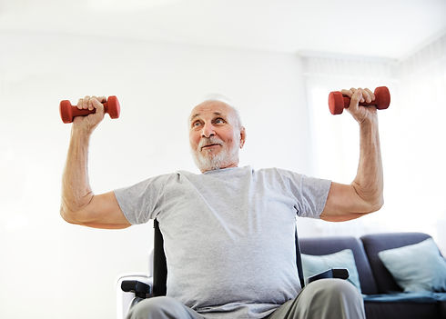 Happy senior man in wheelchair exercising at home or nursing home.jpg