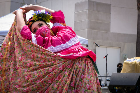 Woman in traditional folk dress and pink mask dancing