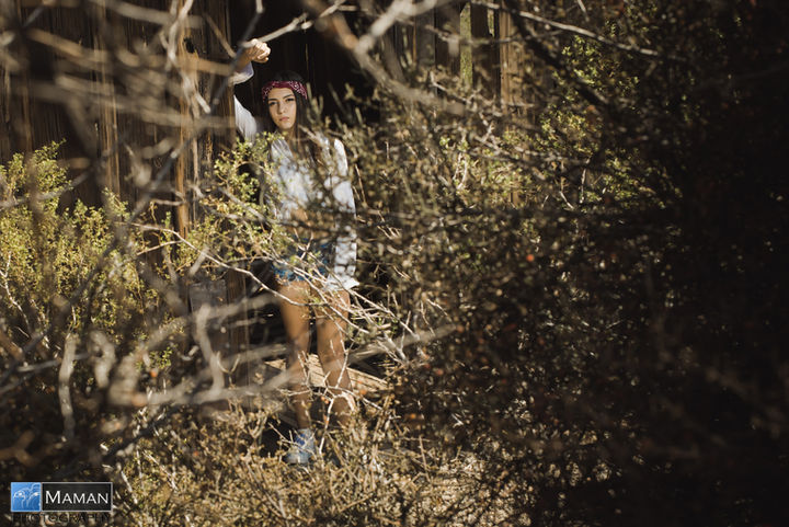 Young woman in a headband posing behind autumn branches.