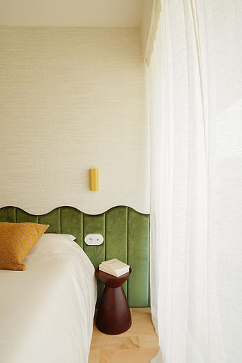 Tête de lit design en velours vert, intégrant des luminaires de chevet et des prises électriques, dans une chambre contemporaine élégante