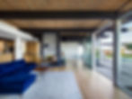 Modern living room interior with a blue sofa, fireplace, and large windows.