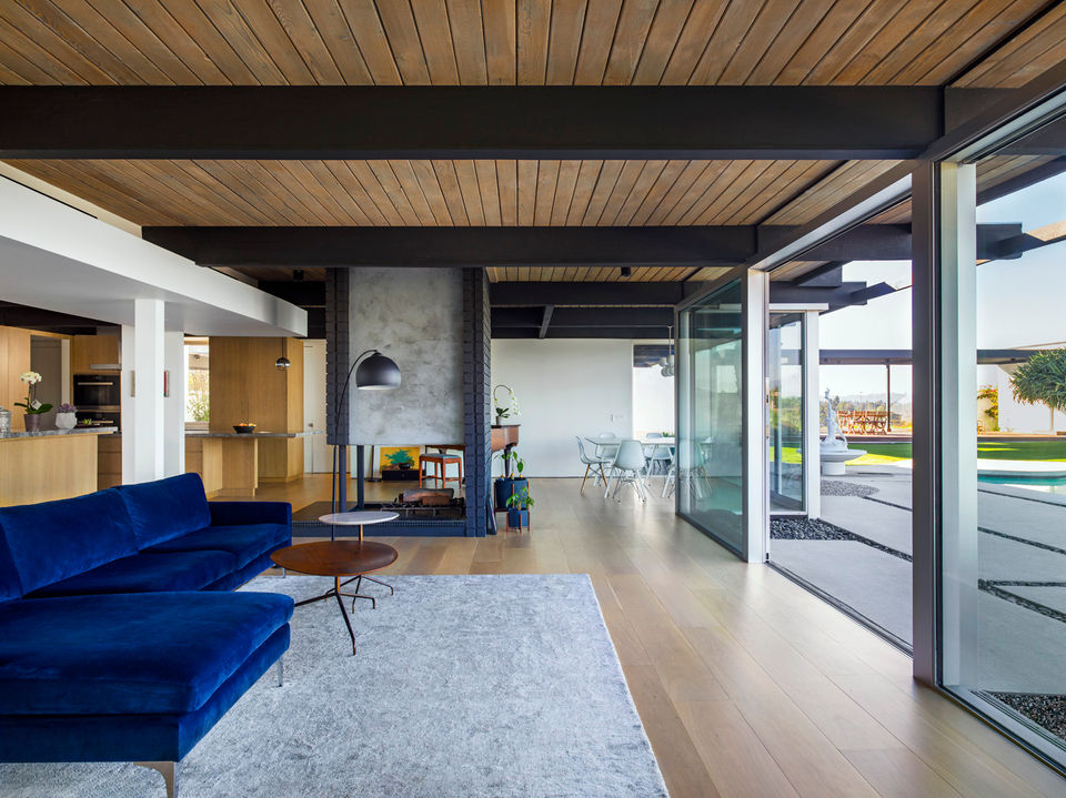 Modern living room with a blue couch, fireplace, and large windows
