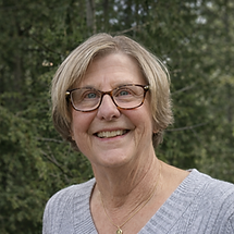 Smiling woman with grey hair outdoors (1).png