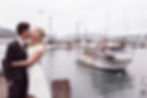 Bride and groom kiss at Careys Bay, Dunedin, while a fisherman cheers them on from his boat