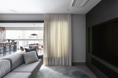 sala de tv com sofá cinza, parede preta e cortina branca