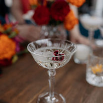 Champagnerschale aus Kristall vor roten und orangenen Blumen