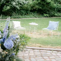 Blumen und Loungecke mit Gartenstühlen im Hintergrund