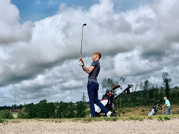 man swinging golf iron