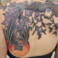 Tattoo of a full color bat hanging upside down on a spooky tree, against the backdrop of a full blood moon