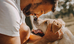 Man smiling while touching his nose to dog's nose