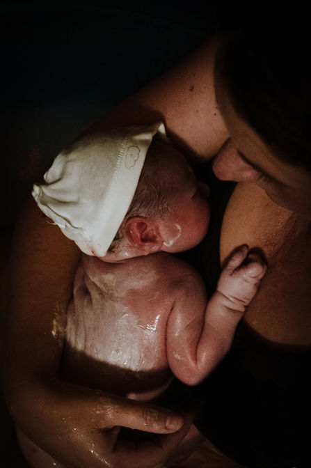 Pasgeboren baby in de armen van moeder, geboortefotograaf voor geplande keizersnede