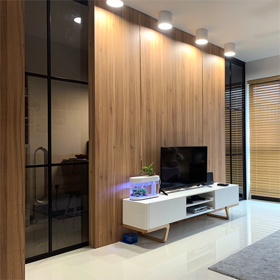 Wood grain TV feature wall serving as a divider to create a study room within the living area; multi-functional; zoning, separating spaces; work-from-home layout