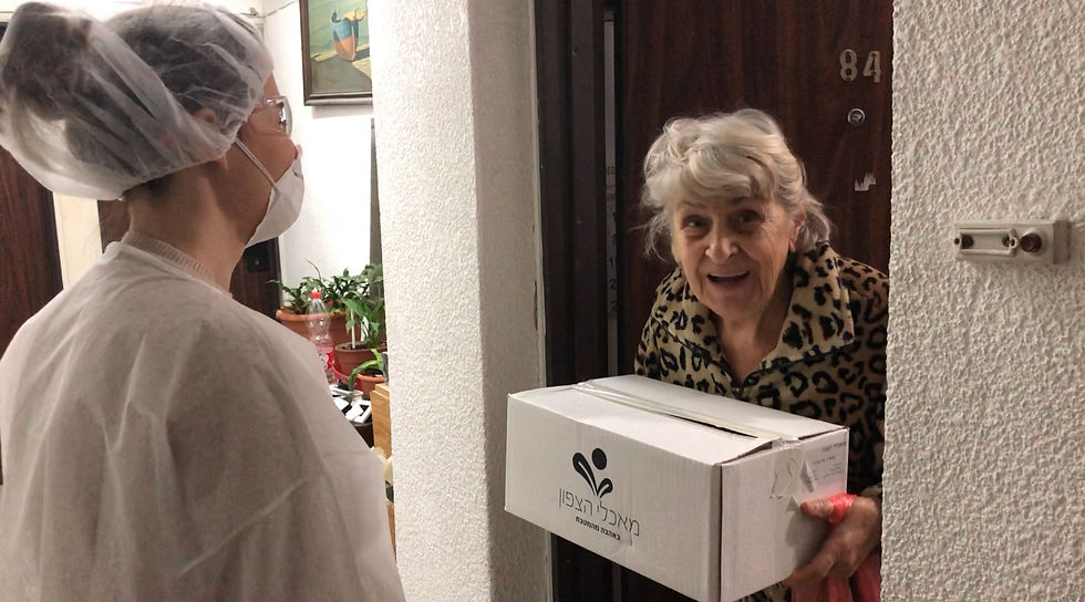 A Leket volunteer delivering a food package to an elderly woman at her door