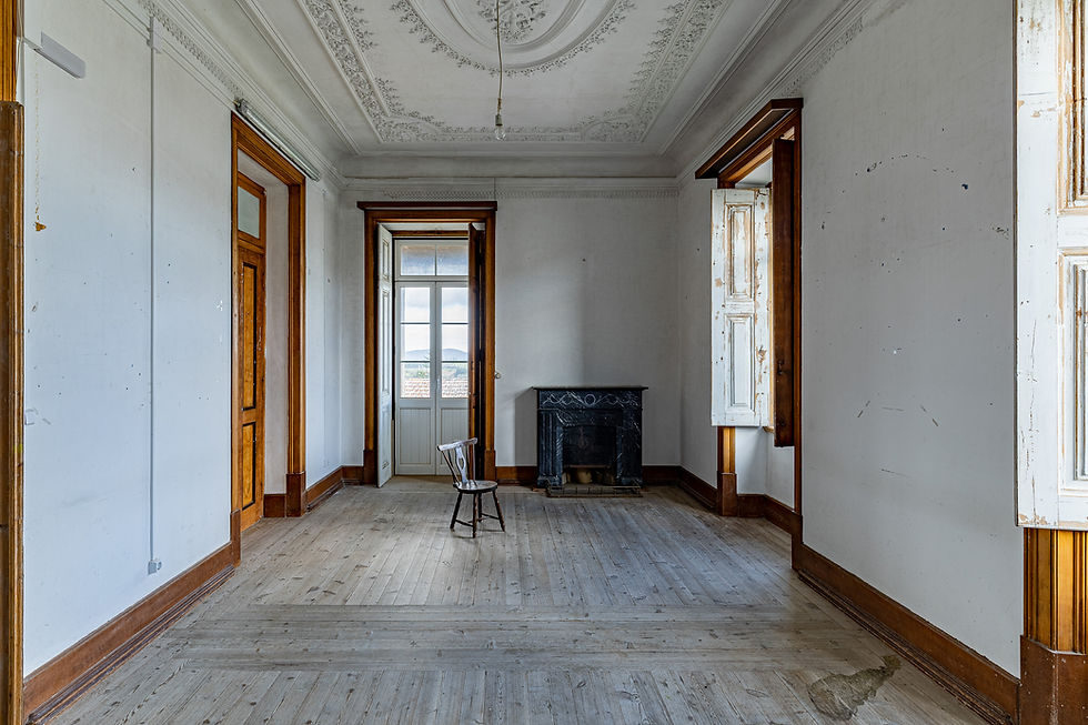 Salon with decorated stucco ceiling, black marble fireplace and wooden floor, manor house in Nisa