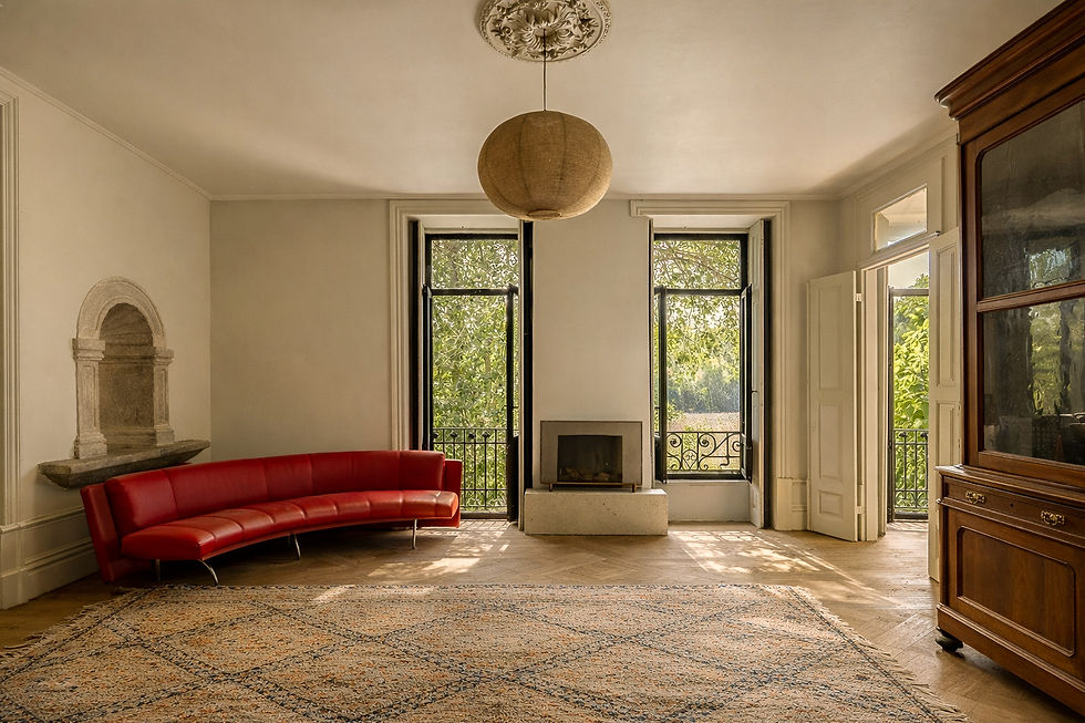 Salon with a stone wall fountain, fireplace and tall windows in a granite house in Campeã, Vila Real