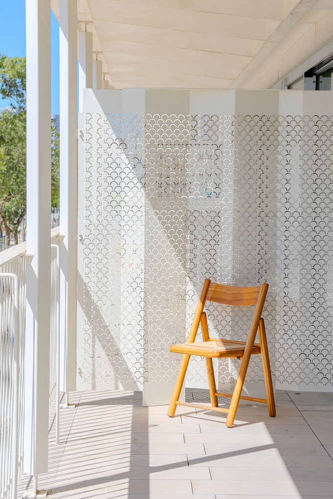 Perforated metal screen and wooden chair on a balcony at Santos Dumont 46