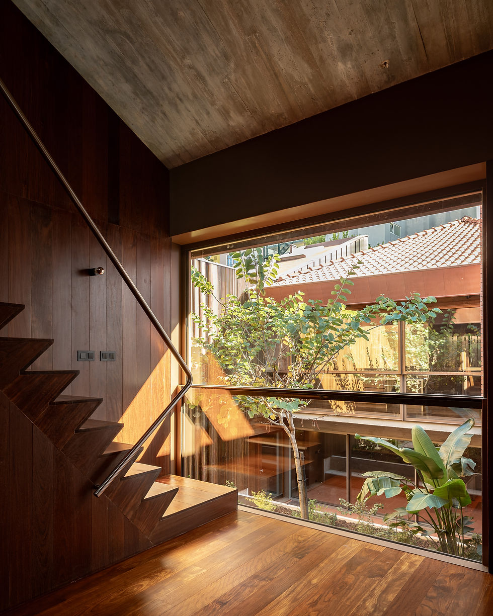 Folded sucupira wood staircase to a mezzanine under a pitched concrete roof, architect-designed Lisbon house