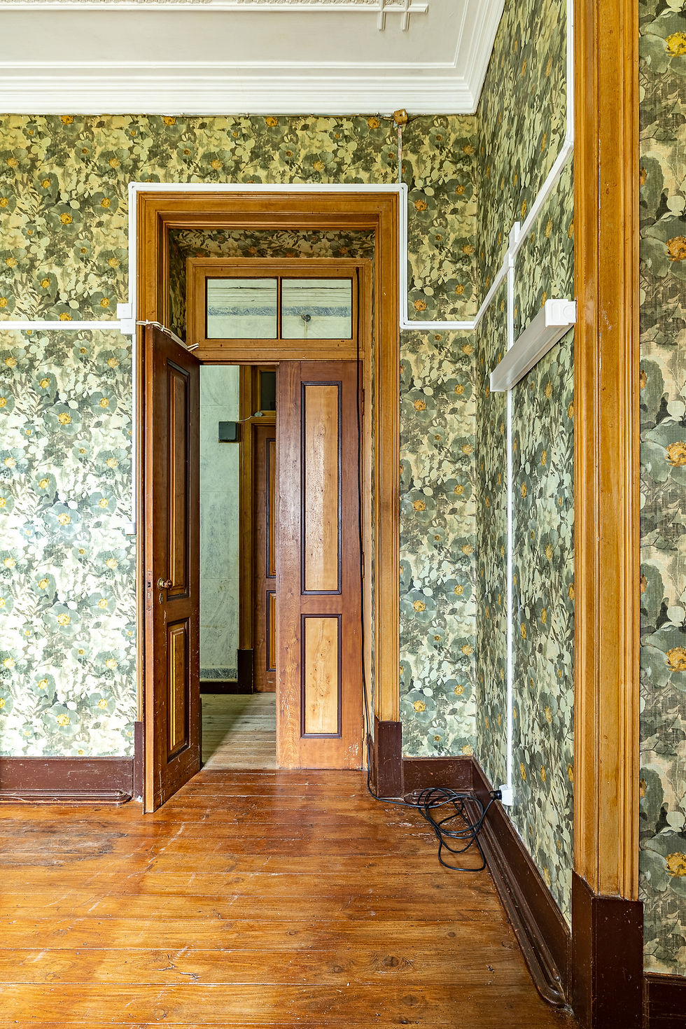Doorway between rooms with floral wallpaper and wooden doors, manor house in Nisa