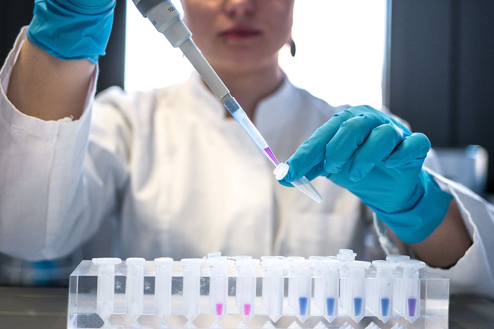 Lab technician in a white coat and blue gloves uses a pipette to transfer purple liquid into a vial, in a bright lab setting.