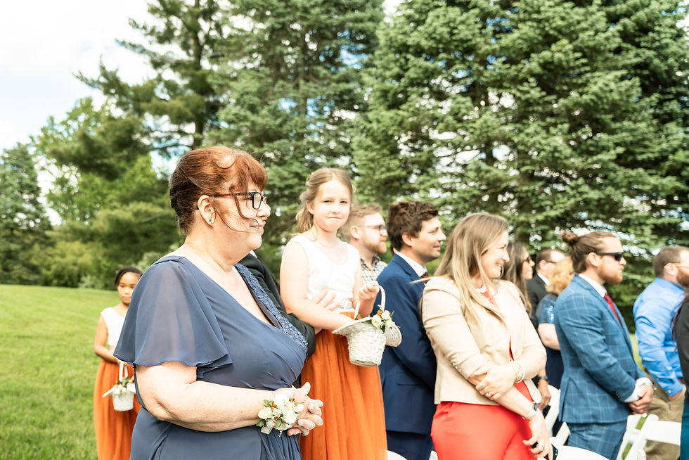 Megan's mom watches her daughter walk down the aisle while Megan's niece stands on a chair to see as over the wedding guests.